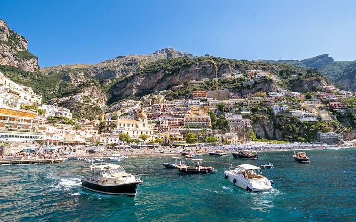 Yacht Destinations — luxury yachts sailing along the Amalfi Coast with the dramatic Italian coastline in the background