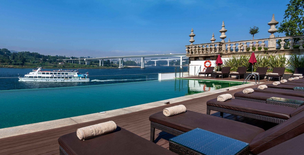 Infinity pool overlooking the river with loungers and passing boat -pestana