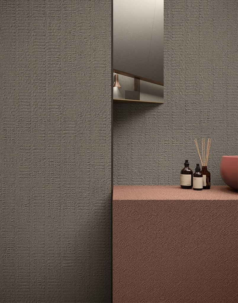 Bathroom detail with textured grey wall and terracotta vanity unit holding aroma diffusers - fall winter 2027 trends