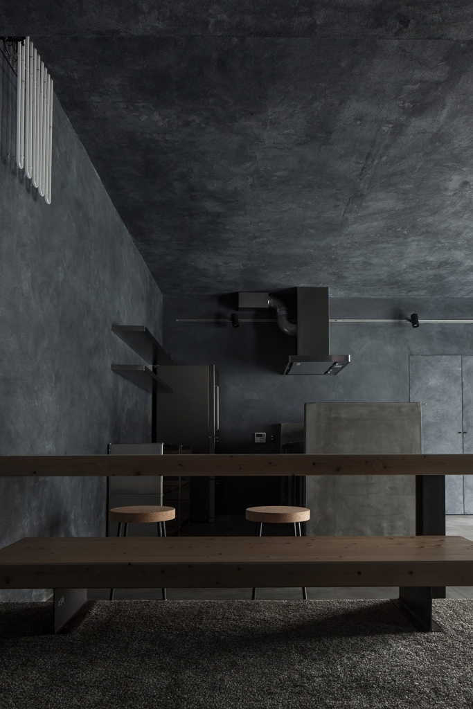 Minimalist grey concrete kitchen loft with cork stools and a long wooden bench - fall winter 2027 trends