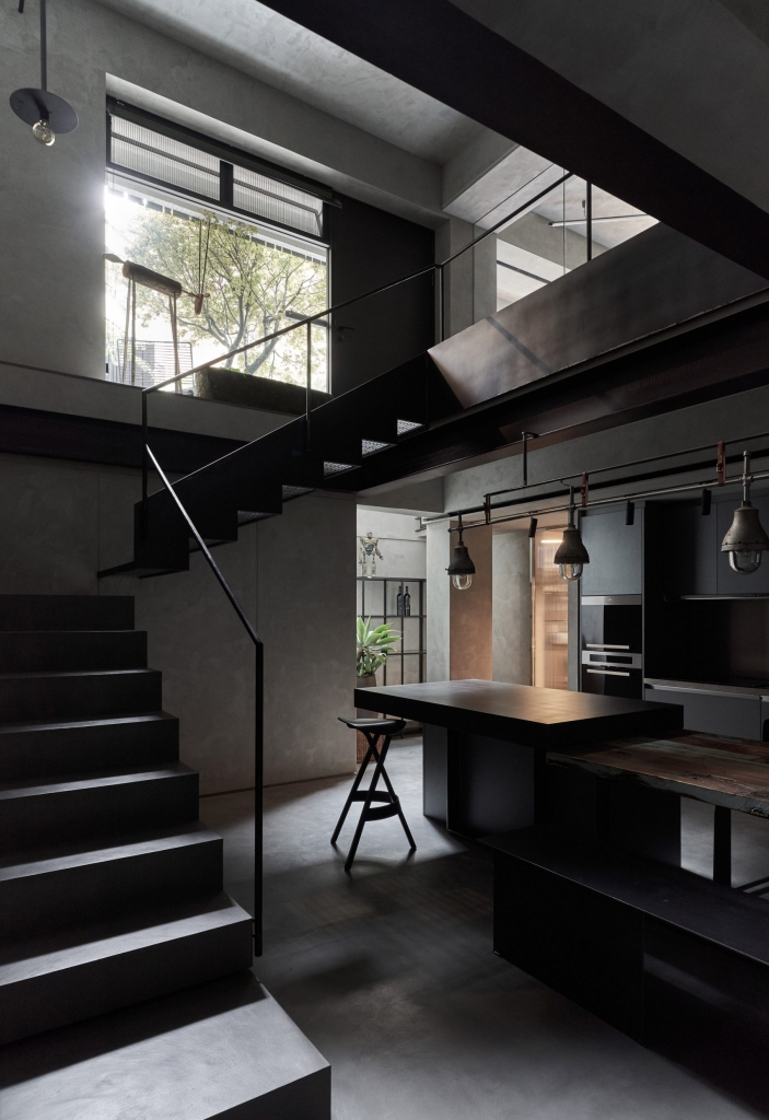Industrial dark loft interior with black staircase, exposed beams and matte black kitchen island - fall winter 2027 trends