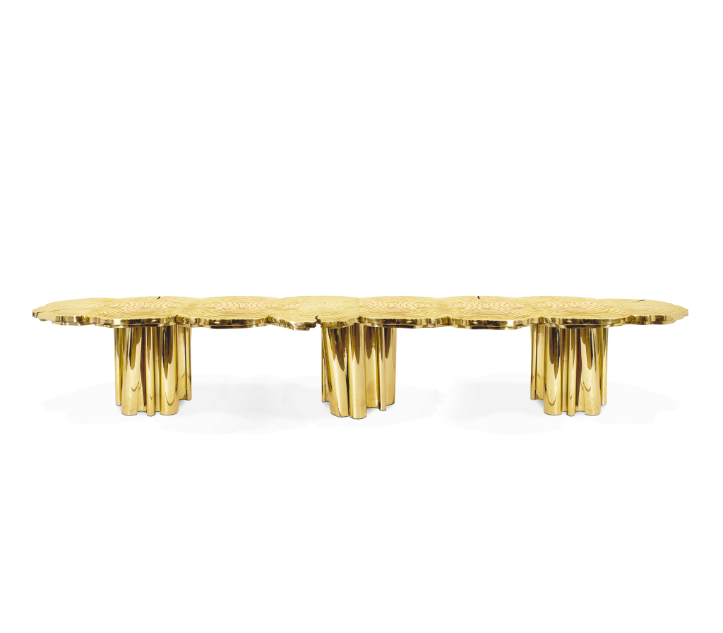 Long gold dining table with tree-ring textured top and fluted cylindrical bases - fall winter 2027 trends