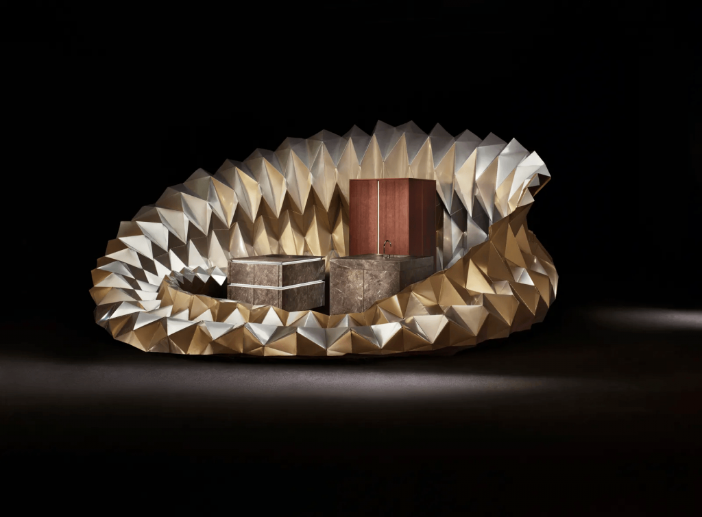 A futuristic, sculptural circular structure with a faceted, metallic gold and silver origami-like exterior enclosing interior modular furniture units against a dark background. design democracy