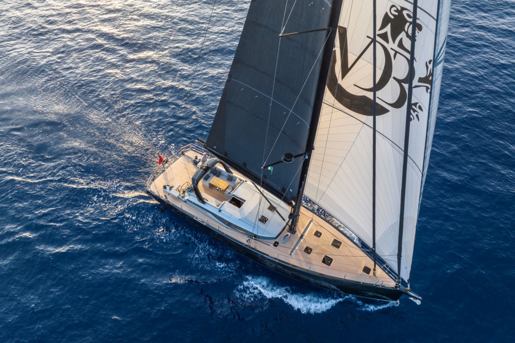 A modern sailing yacht navigating through deep blue ocean waters with large black sails up at the Cannes Yachting Festival 2026.