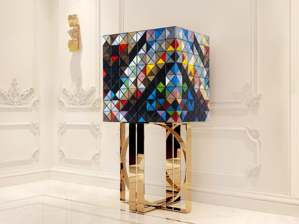 Contemporary Living Room Ideas showcasing an exclusive pixelated cabinet standing on a polished gold geometric base inside a bright room with classic white wall paneling.