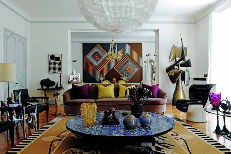 Eclectic living room featuring a purple sofa, large round blue mosaic coffee table, and geometric artwork., interior designer trends 2027