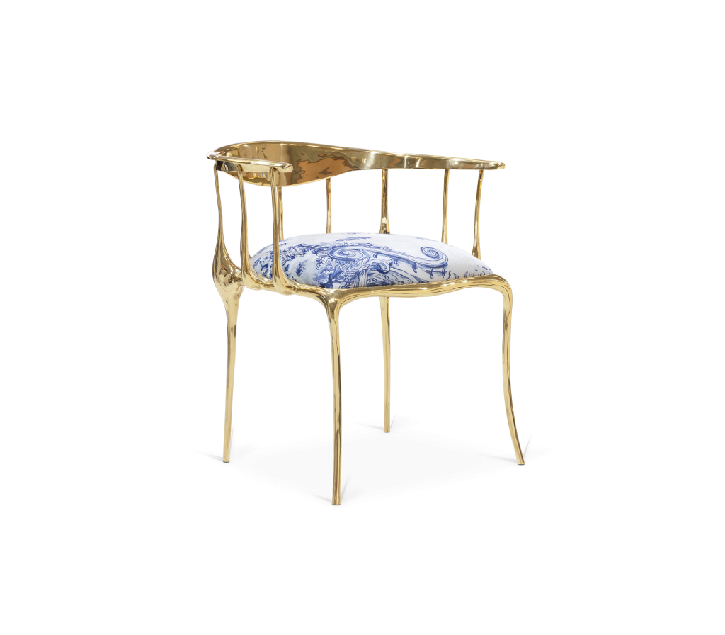 Gold sculptural armchair with a blue and white patterned seat cushion - fall winter 2027 trends