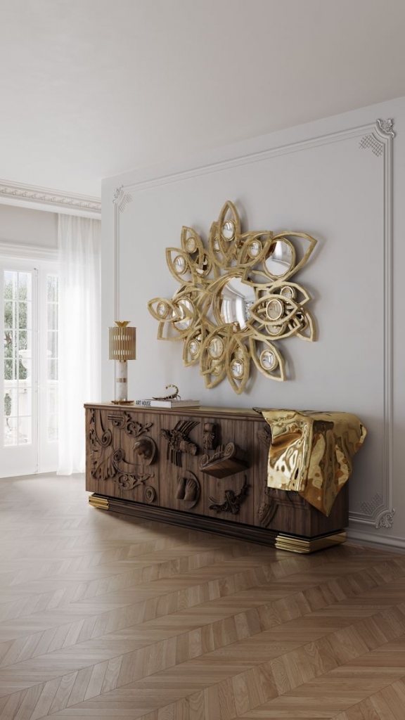 Voltaire Walnut sideboard with sculptural hand-carved wood details and a draped molten-gold accent, beneath a floral gold mirror – statement sideboard.