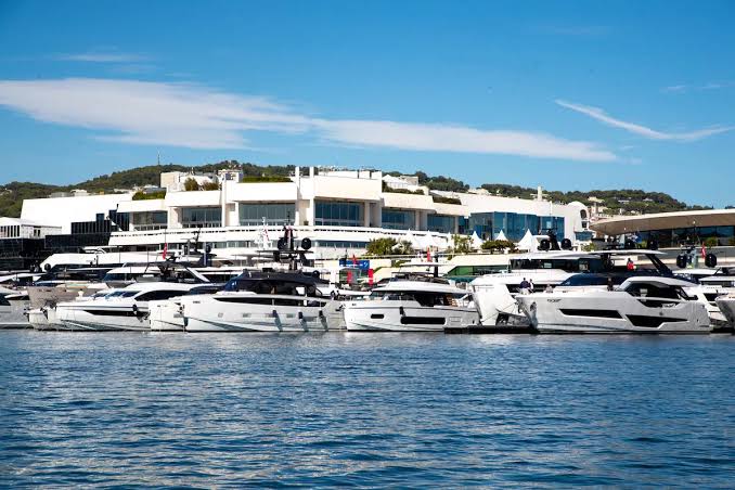 A wide-angle view of multiple luxury motor yachts docked neatly side by side in a bustling marina during the Cannes Yachting Festival 2026.