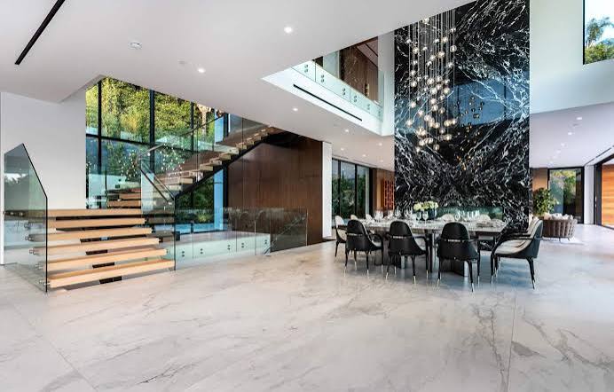 A grand modern dining space with a striking black and white marble accent wall, a glass-topped dining table with black chairs, and a contemporary multi-bulb chandelier at luxury furniture showrooms in Monaco.