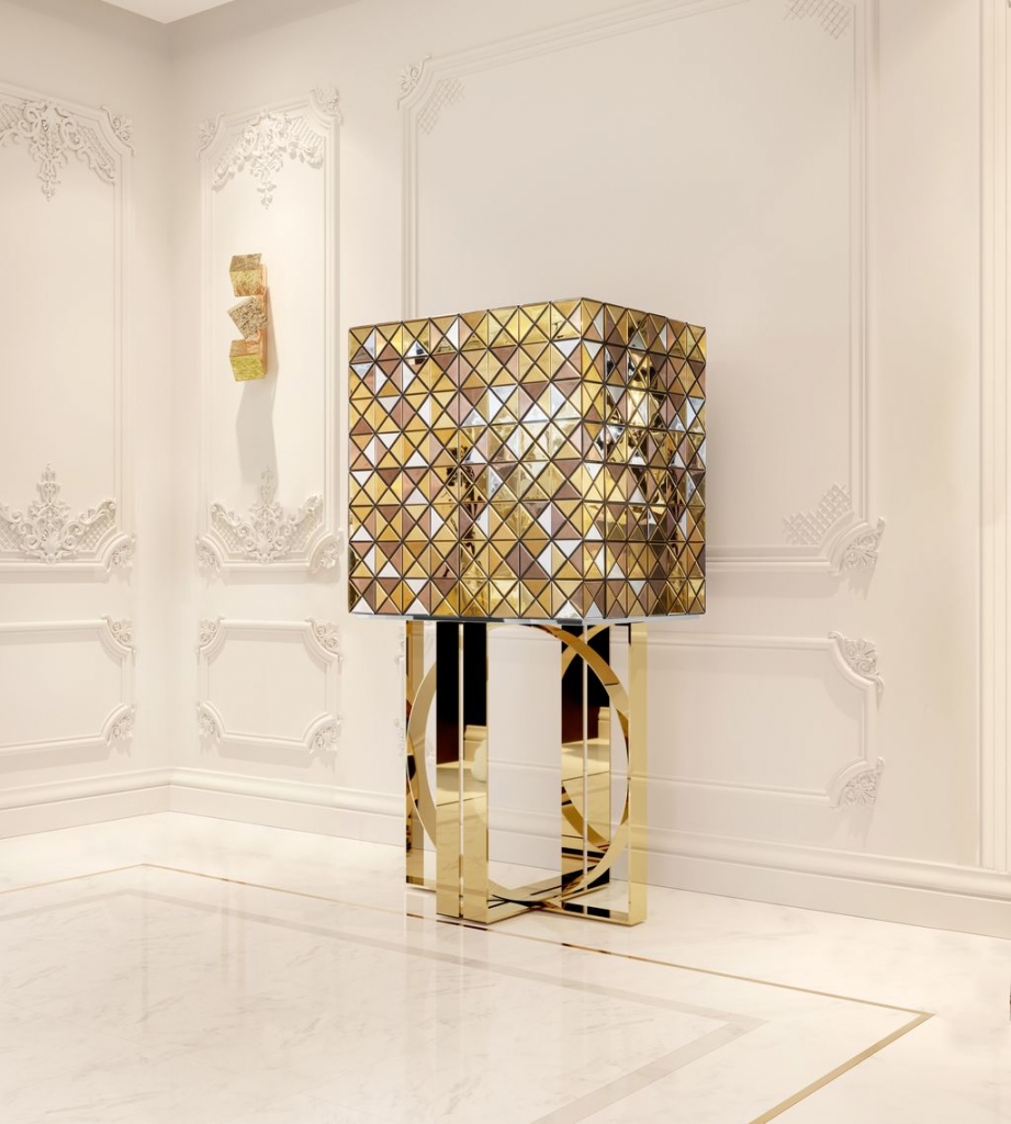 Gold mirrored Pixel cabinet with triangular faceted panels on a circular gold ring base, displayed against a cream boiserie wall – statement sideboard.