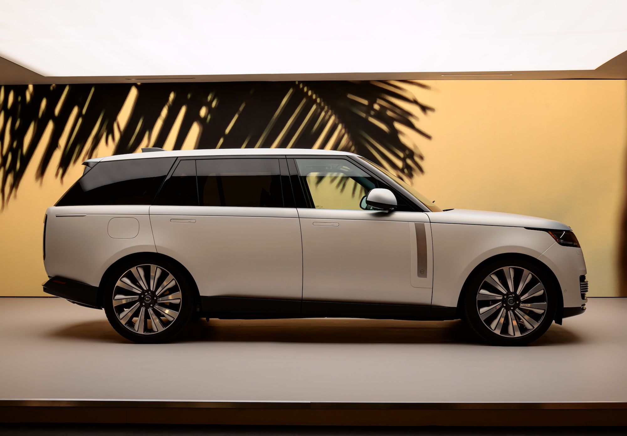 Side profile view of a luxury white SUV displayed against a warm backdrop with palm tree silhouettes Design Miami.Paris 2026