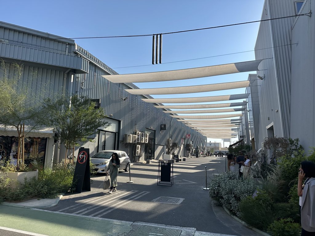Outdoor pedestrian alley lined with industrial metal warehouses and shade canopy sails in Alserkal Avenue.