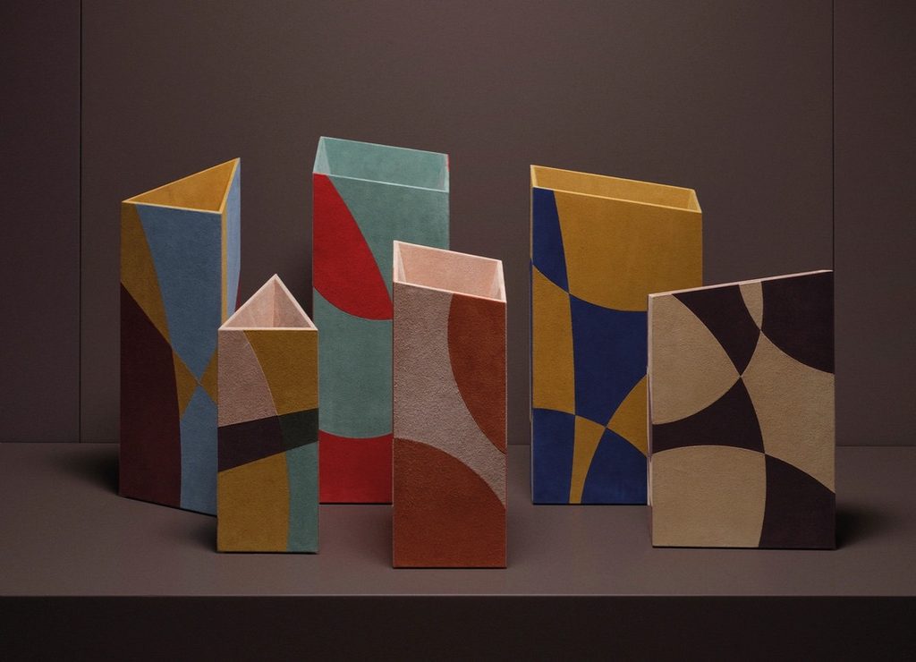 A collection of angular ceramic vases featuring geometric color blocks in muted earth tones, blue, yellow, and red Design Miami.Paris 2026